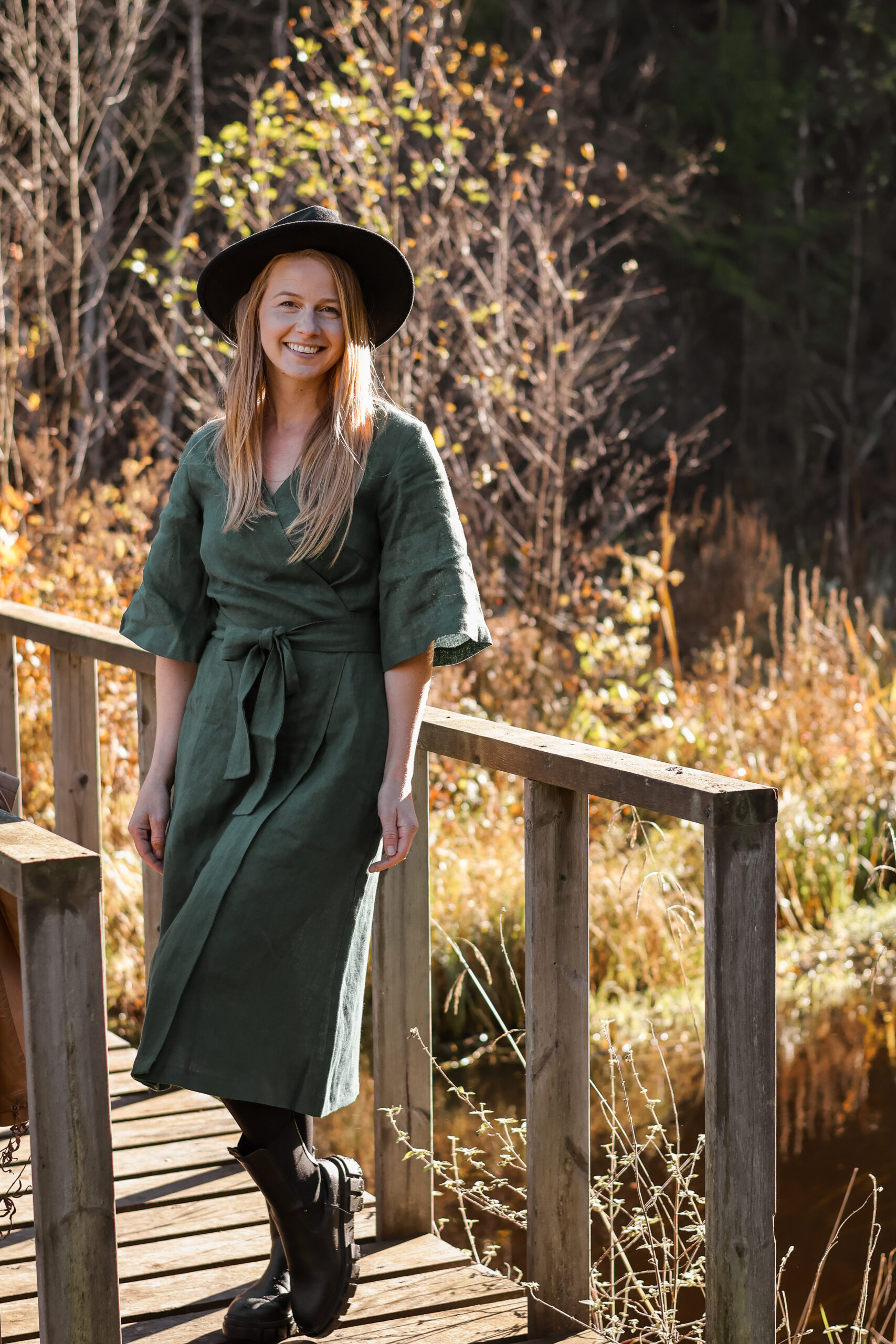 Naine rohelises wrap-lõikelises kimono stiilis linases kleidis sügiseses looduses.